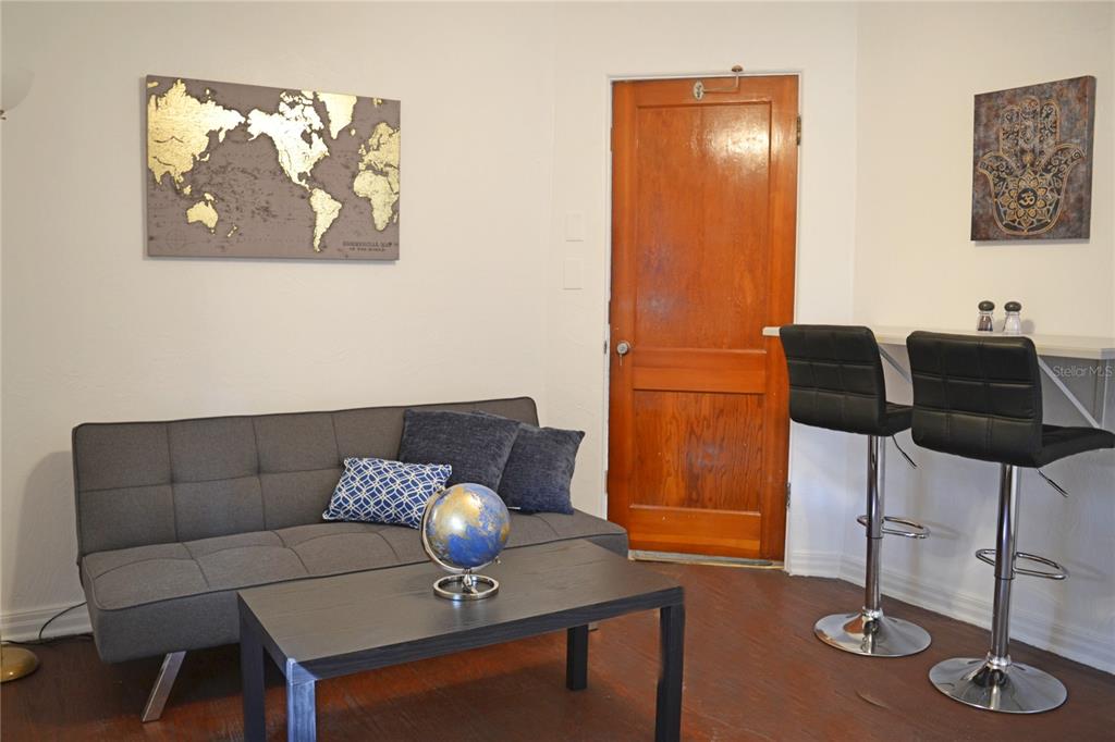 A living room features a gray sofa, a coffee table with a globe, and bar seating — 3120 PEEL AVENUE UNIT 3, ORLANDO, FL