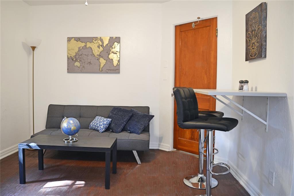 A small living area features a gray sofa, a coffee table, and a wall-mounted breakfast bar — 3120 PEEL AVENUE UNIT 3, ORLANDO, FL