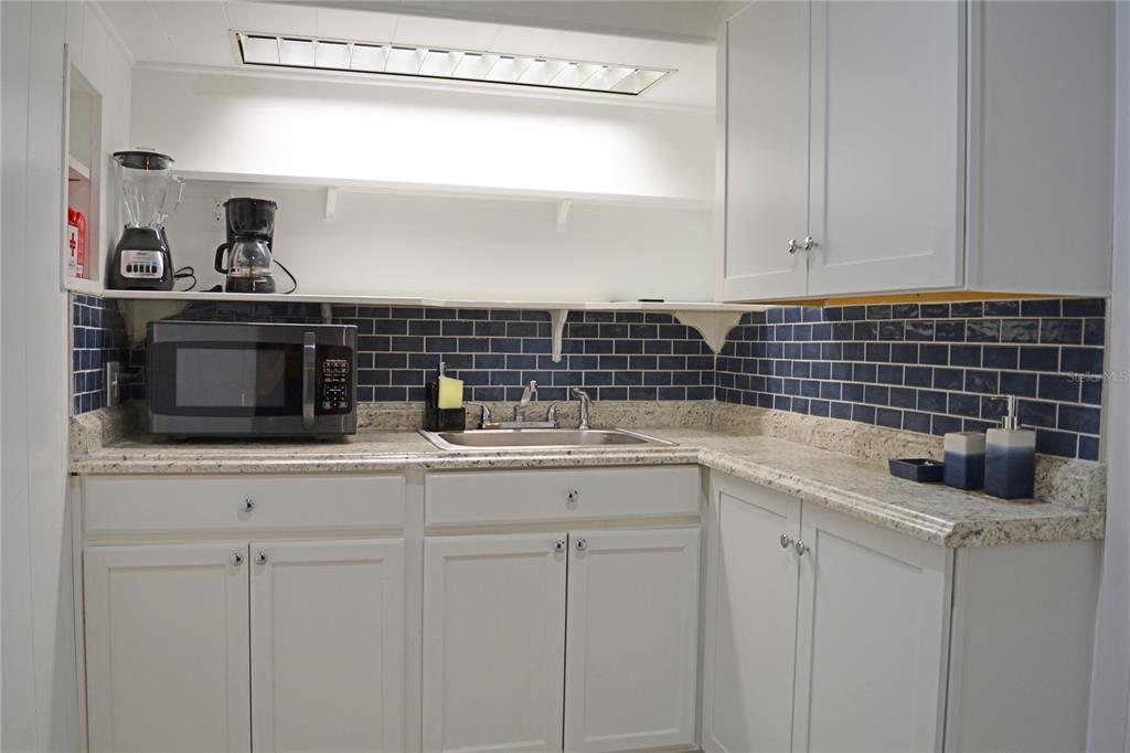 A kitchen features white cabinets, granite countertops, and a blue subway tile backsplash — 3120 PEEL AVENUE UNIT 3, ORLANDO, FL