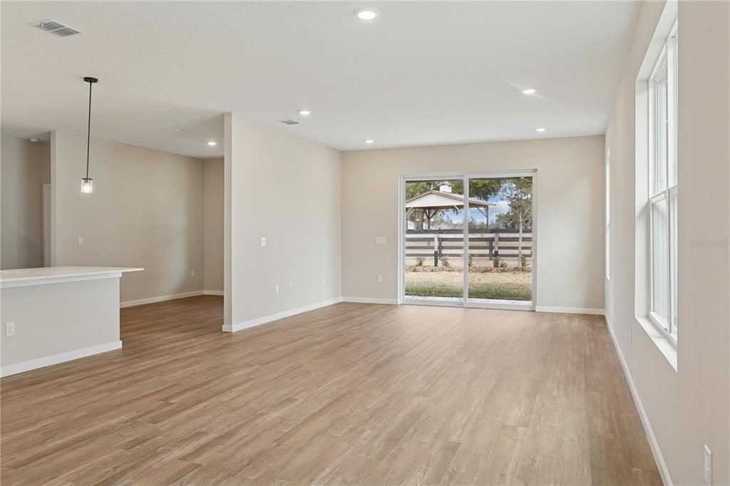 An open-concept living area features light wood-look flooring, recessed lighting, and a sliding glass door — 4449 NW 37TH STREET ROAD, OCALA, FL