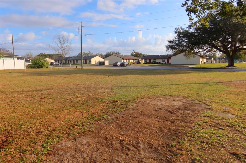 A vacant, grassy lot sits in front of several single-story residential buildings — NORTH AVENUE, ZEPHYRHILLS, FL