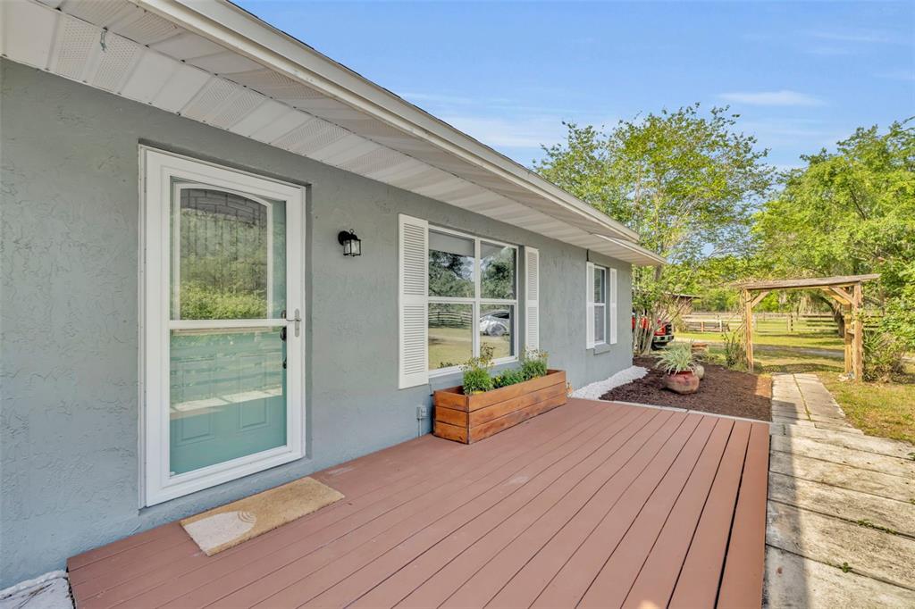 A gray house exterior features a wooden deck, a window box, and a storm door — 430 CYPRESS ISLES ROAD, OSTEEN, FL