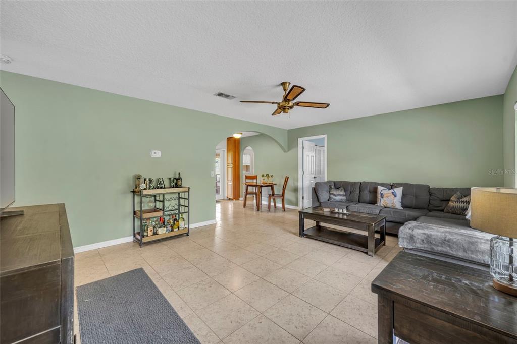 A living room with light green walls, tile flooring, a sectional sofa, and a bar cart — 430 CYPRESS ISLES ROAD, OSTEEN, FL