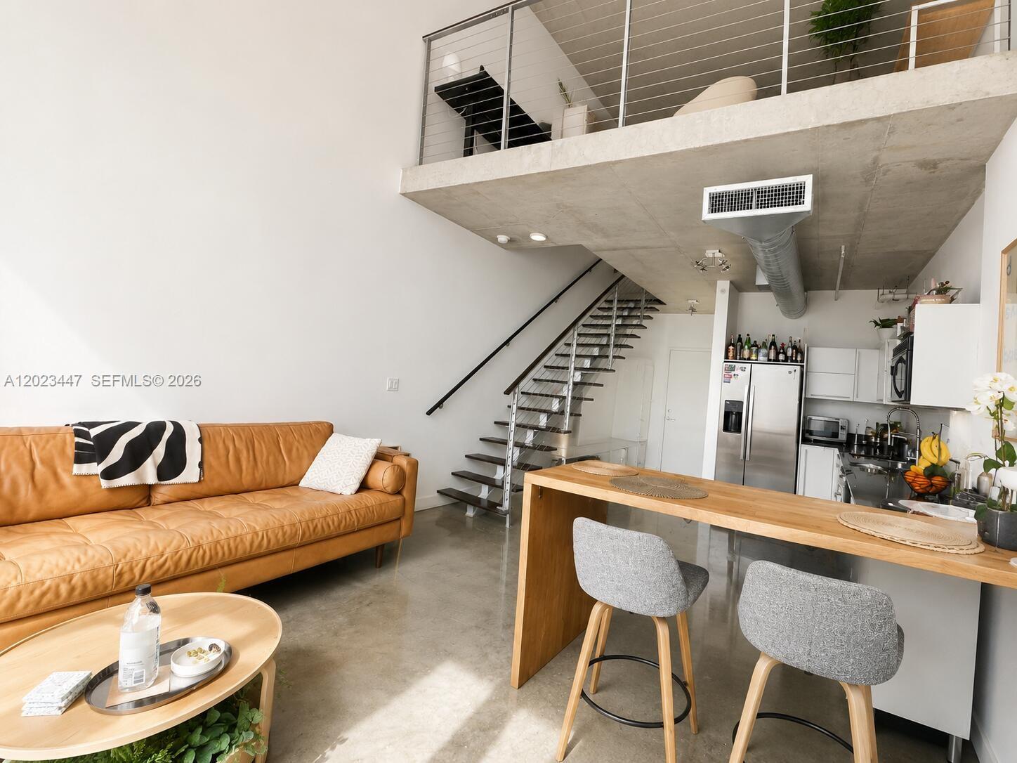 A modern loft living area features a leather sofa, kitchen island, and an open staircase — 690 SW 1st Ct # 2314, Miami FL 33130, MIAMI, FL
