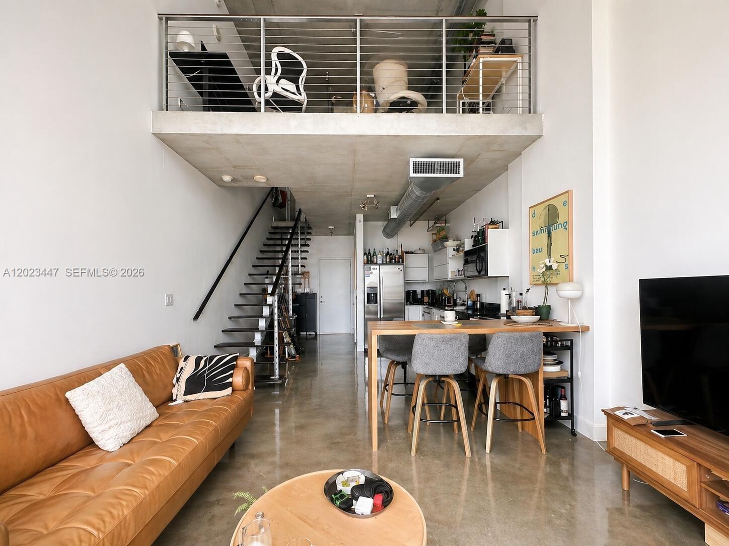 A modern loft apartment features a concrete ceiling, mezzanine level, staircase, and open-plan living area — 690 SW 1st Ct # 2314, Miami FL 33130, MIAMI, FL
