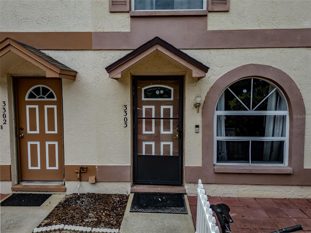 The exterior of two adjacent townhome units features brown doors with glass inserts and windows — 3303 BRIGADOON DRIVE, CLEARWATER, FL
