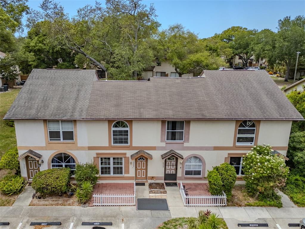 An exterior view of a two-story townhouse complex with a shingled roof and patios — 3303 BRIGADOON DRIVE, CLEARWATER, FL