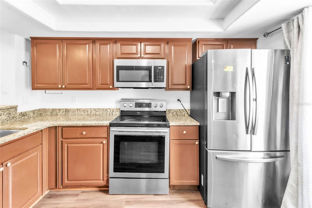 A kitchen features wood cabinets, granite countertops, and stainless steel appliances — 3303 BRIGADOON DRIVE, CLEARWATER, FL