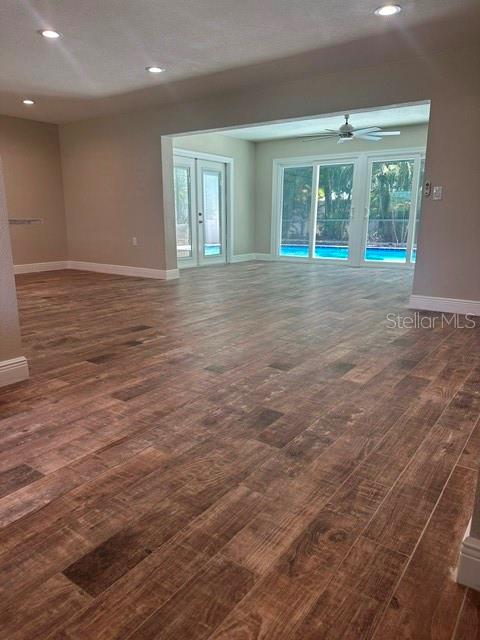 An open living area features wood-look tile flooring and sliding glass doors overlooking a swimming pool — 103 CARLYLE DRIVE, PALM HARBOR, FL
