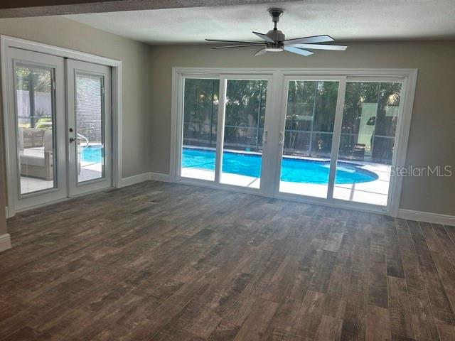 A room with wood-look tile flooring features a ceiling fan and sliding glass doors overlooking a pool — 103 CARLYLE DRIVE, PALM HARBOR, FL