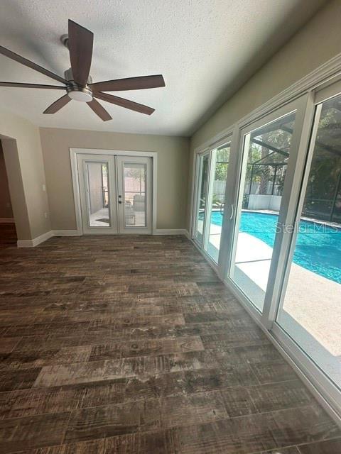 A room with wood-look tile flooring, a ceiling fan, and sliding glass doors overlooking a pool — 103 CARLYLE DRIVE, PALM HARBOR, FL