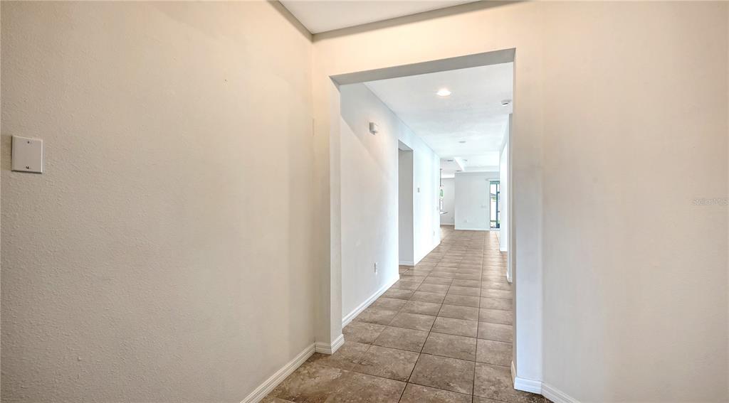 A tiled hallway leads from a neutral-walled entryway into an open-concept living area — 15127 LAS OLAS PLACE, BRADENTON, FL