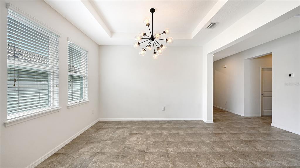 A dining room with tile flooring, a tray ceiling, and a modern sputnik chandelier — 15127 LAS OLAS PLACE, BRADENTON, FL