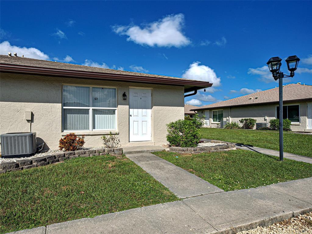 A single-story tan stucco building with a white front door and a concrete walkway — 21150 GERTRUDE AVENUE UNIT G3, PORT CHARLOTTE, FL