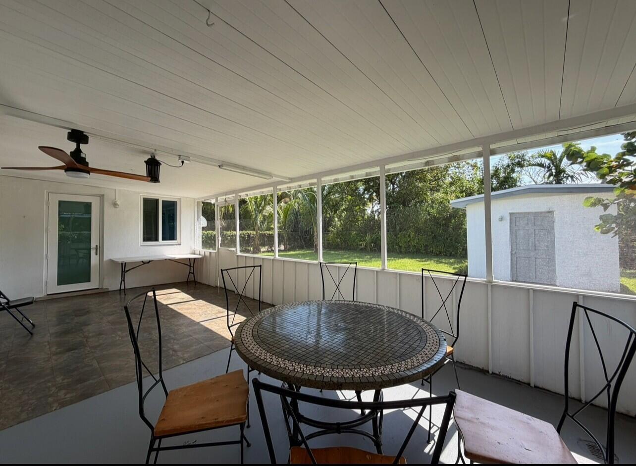 A screened-in patio features a tiled floor, a round mosaic table, and a ceiling fan — 206 NE 5th Avenue, Dania Beach FL 33004, DANIA BEACH, FL
