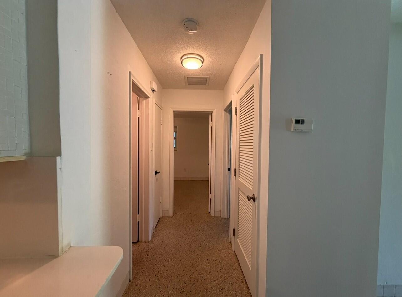 A hallway with carpeted flooring, white walls, and several closed doors leading to other rooms — 206 NE 5th Avenue, Dania Beach FL 33004, DANIA BEACH, FL