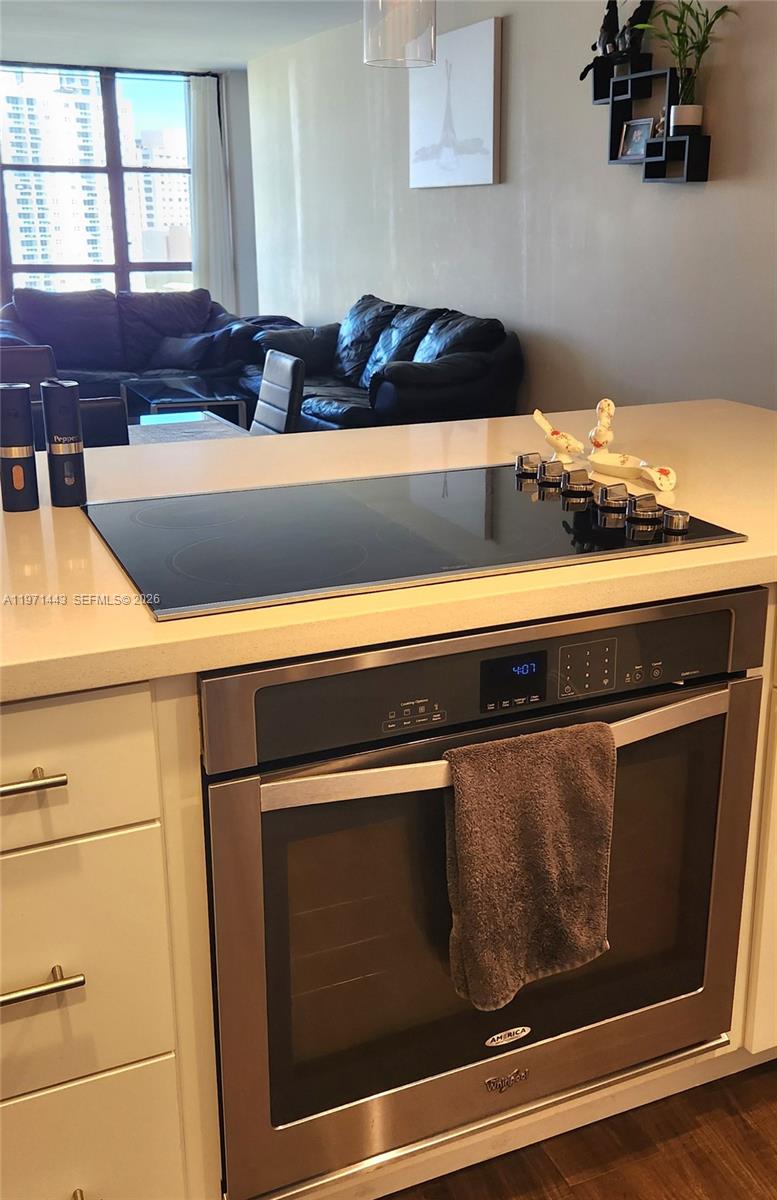 A kitchen island features a built-in electric cooktop and oven with white cabinetry — 1000 Parkview Dr # 1026, Hallandale Beach FL 33009, HALLANDALE BEACH, FL