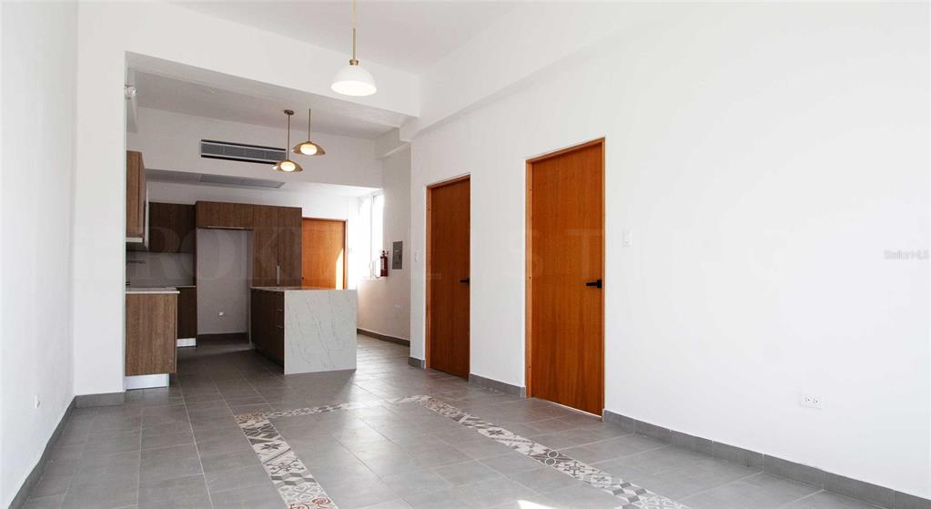 An open-concept room features a kitchen with a marble island, tile floors, and wooden doors — 319 RECINTO SUR STREET UNIT 5, SAN JUAN, PR