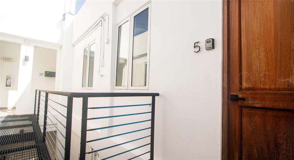A wooden door with a lockbox sits next to a window on a white exterior walkway — 319 RECINTO SUR STREET UNIT 5, SAN JUAN, PR