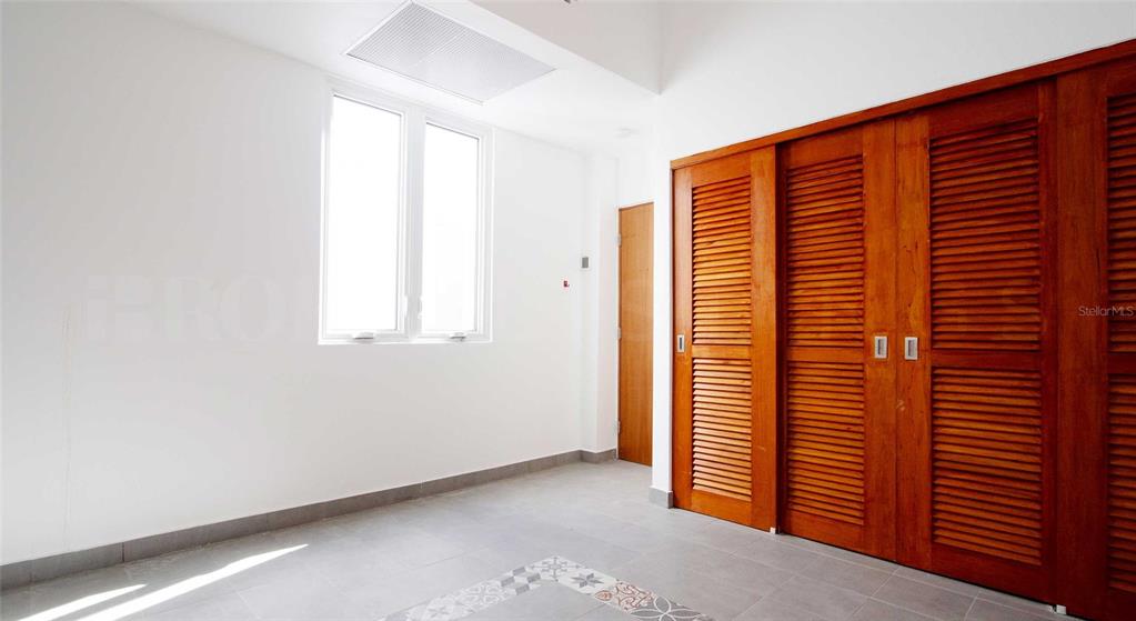 A room with white walls, tile flooring, a window, and wooden louvered closet doors — 319 RECINTO SUR STREET UNIT 5, SAN JUAN, PR