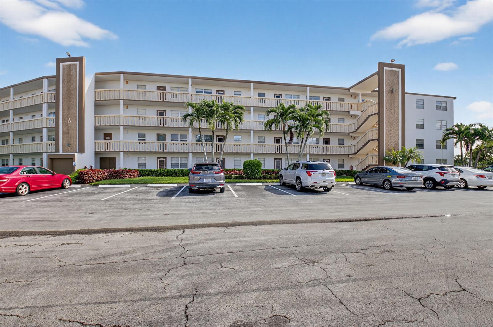 A multi-story apartment building with a parking lot in the foreground under a blue sky — 3005 Guildford A, Boca Raton FL 33434, BOCA RATON, FL