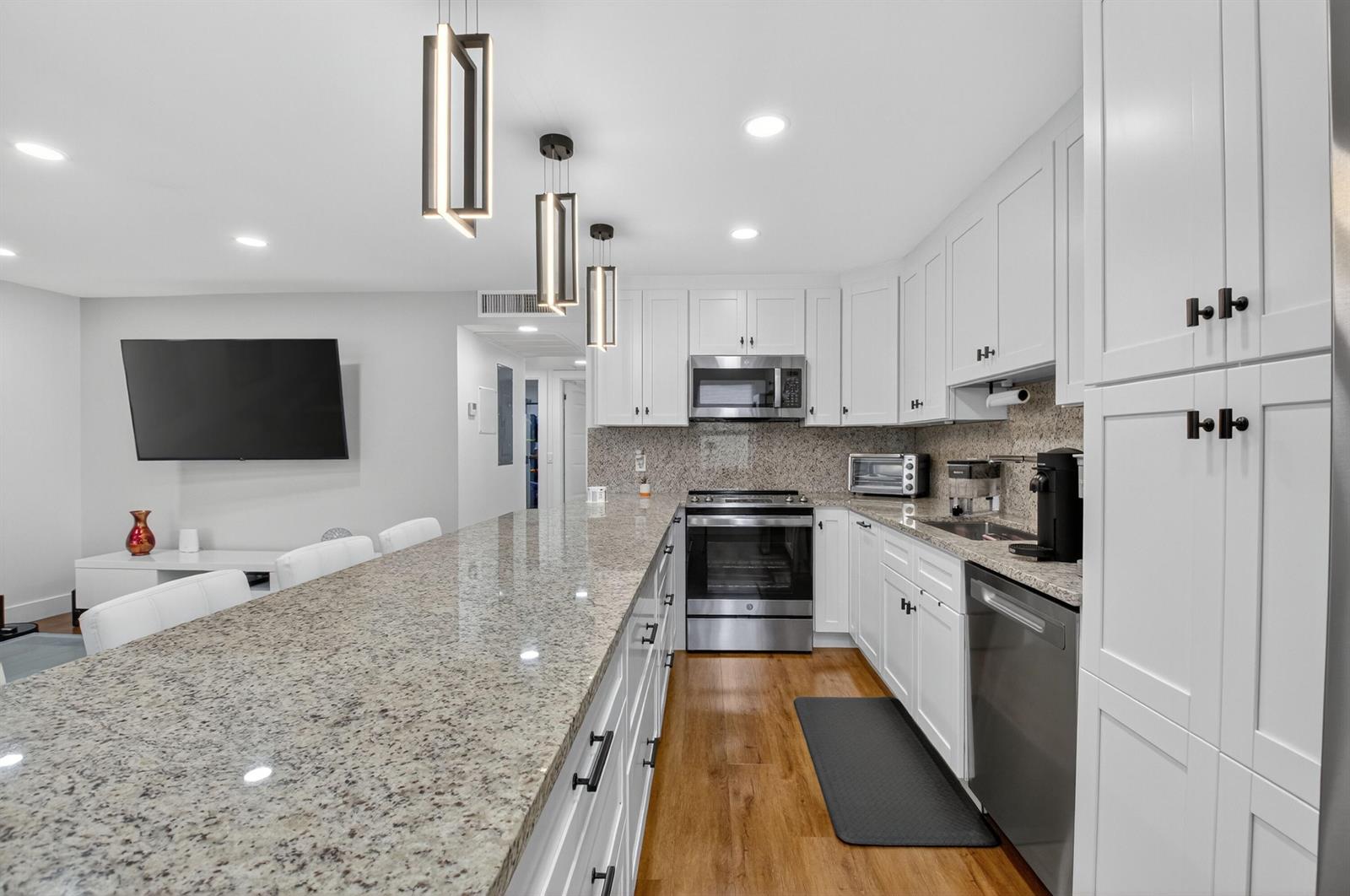 A kitchen features white cabinets, granite countertops, stainless steel appliances, and a long breakfast bar — 3005 Guildford A, Boca Raton FL 33434, BOCA RATON, FL