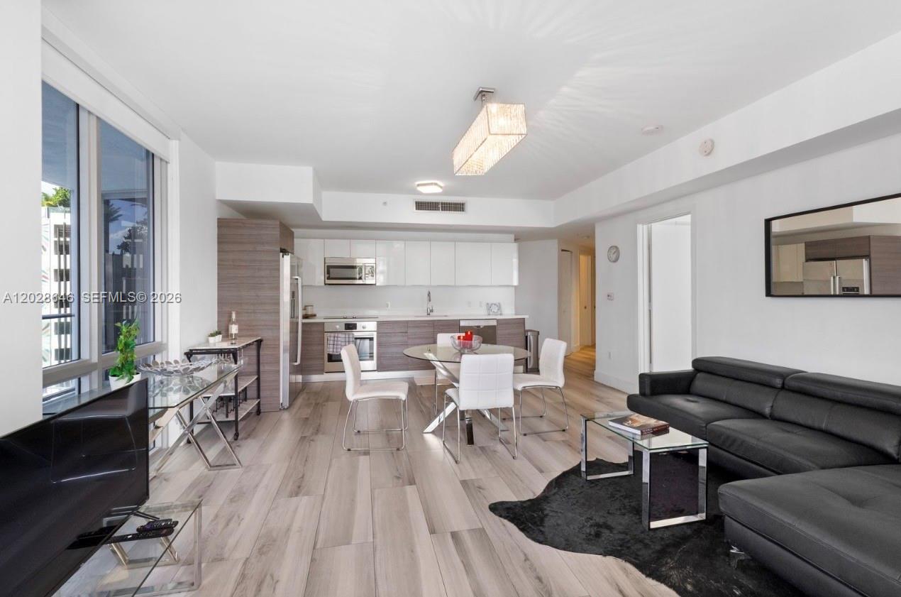 This open-concept living and dining area features light wood flooring and a modern kitchen — 1010 SW 2nd Ave # 609, Miami FL 33130, MIAMI, FL