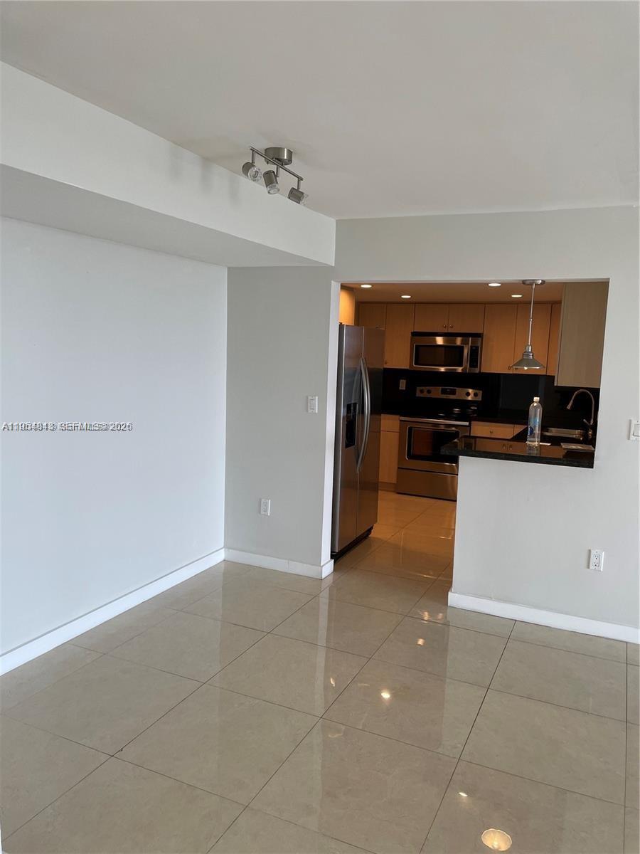 A kitchen with stainless steel appliances and a breakfast bar opens into a tiled room — 13155 Ixora Ct # 901, North Miami FL 33181, NORTH MIAMI, FL