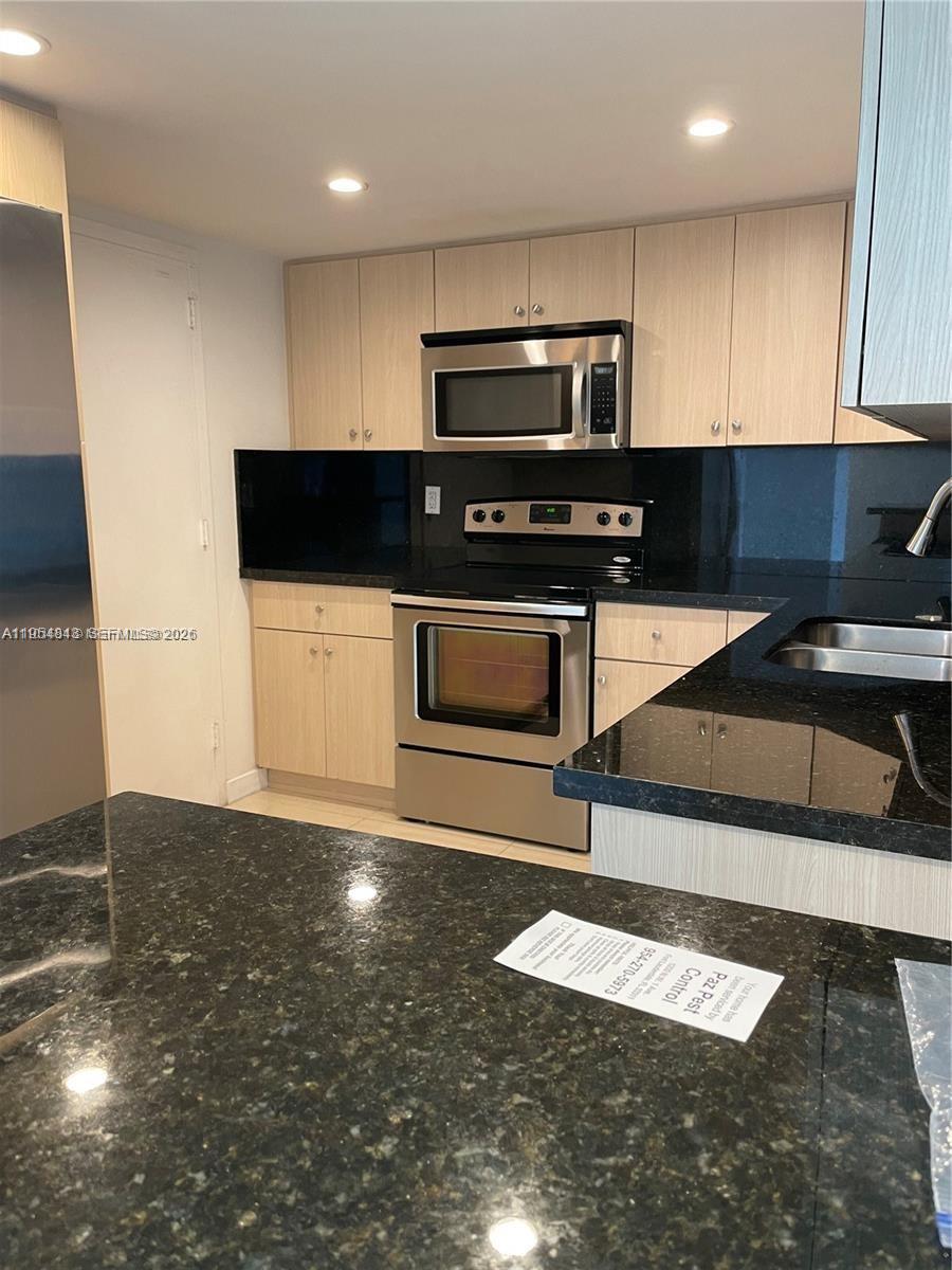 A kitchen features light wood cabinets, black granite countertops, and stainless steel appliances — 13155 Ixora Ct # 901, North Miami FL 33181, NORTH MIAMI, FL