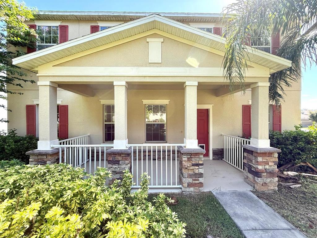 A two-story house exterior features a covered front porch with stone-based columns and red shutters — 2054 BLAIRMOOR PLACE, APOPKA, FL
