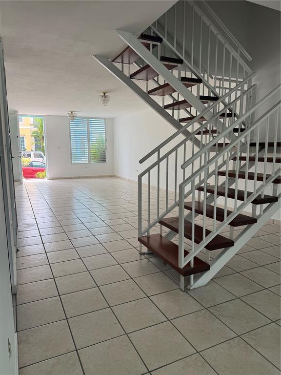 An open living area features white tile floors and a staircase with wooden treads — 0 BESO DE MAR UNIT A13, CAROLINA, PR