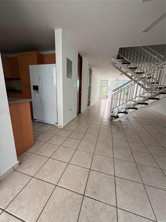 A tiled living area features a kitchen with wood cabinets and a white staircase — 0 BESO DE MAR UNIT A13, CAROLINA, PR
