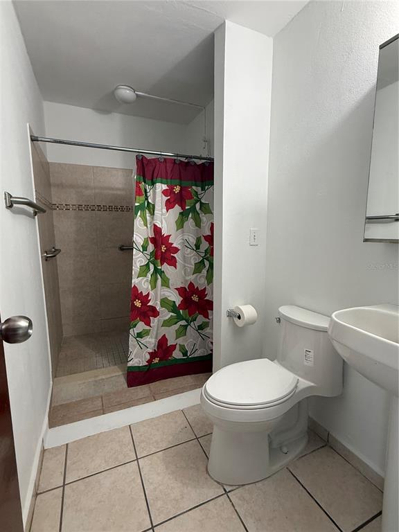 A bathroom features a walk-in shower with a floral curtain, a toilet, and a pedestal sink — 0 BESO DE MAR UNIT A13, CAROLINA, PR