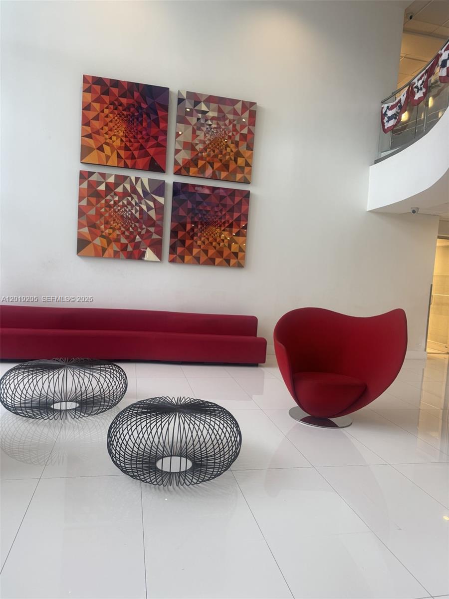 A modern lobby features a red sofa, a red accent chair, and two wire coffee tables — 5701 Collins Ave # 511, Miami Beach FL 33140, MIAMI BEACH, FL