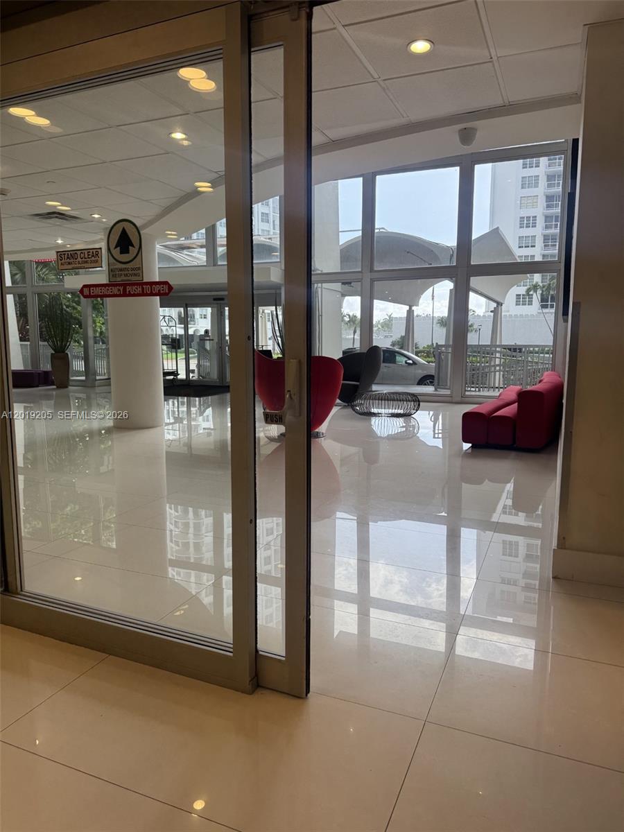 A bright lobby features glass sliding doors, white tile floors, and modern red seating — 5701 Collins Ave # 511, Miami Beach FL 33140, MIAMI BEACH, FL