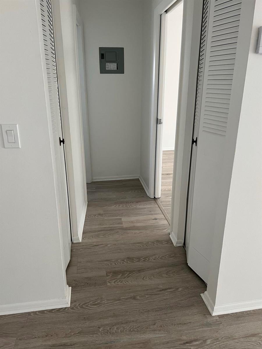 A hallway with light wood-look flooring, white walls, and two louvered closet doors — 2736 Dudley Drive E # I, West Palm Beach FL 33415, WEST PALM BEACH, FL