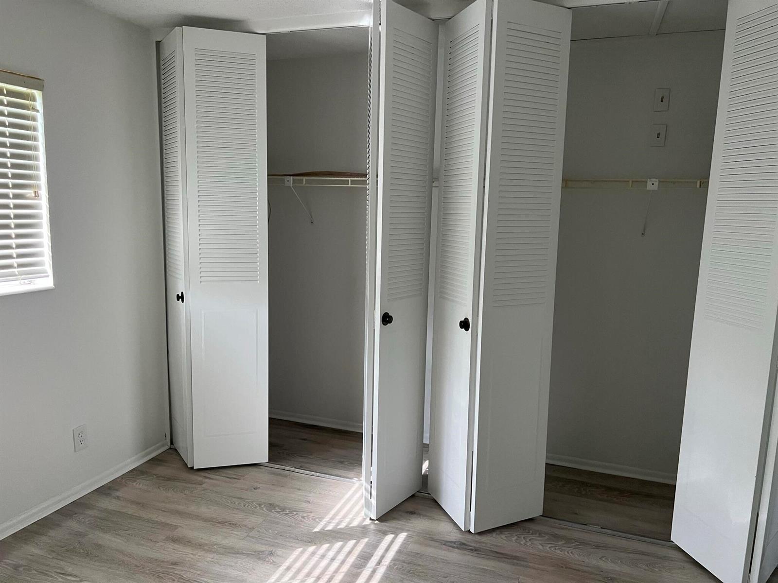 A bedroom features light wood-look flooring, white walls, and a double-door louvered closet — 2736 Dudley Drive E # I, West Palm Beach FL 33415, WEST PALM BEACH, FL