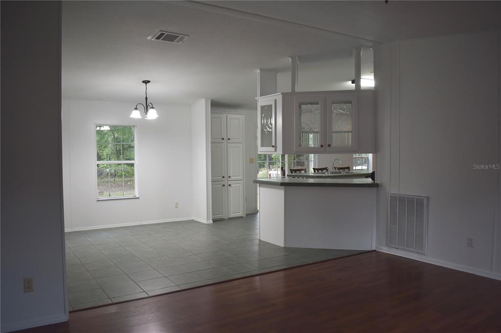 A dining area with tile flooring transitions into a kitchen with a breakfast bar — 8231 NE 111TH STREET, BRONSON, FL