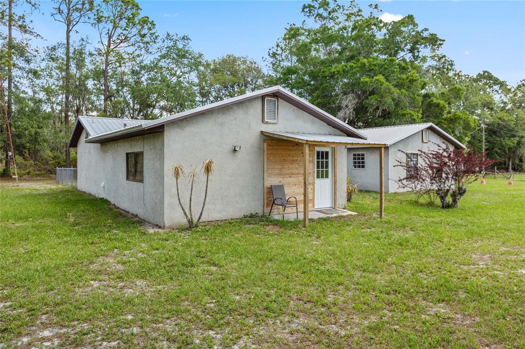 A single-story stucco house with a metal roof and a small wooden-accented front porch — 11115 SW 105TH STREET, BROOKER, FL