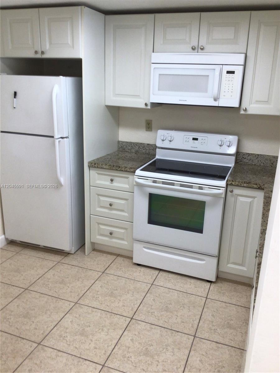 A kitchen features white cabinets, a white refrigerator, a white stove, and granite countertops — 10975 SW 107th St # 302, Miami FL 33176, MIAMI, FL