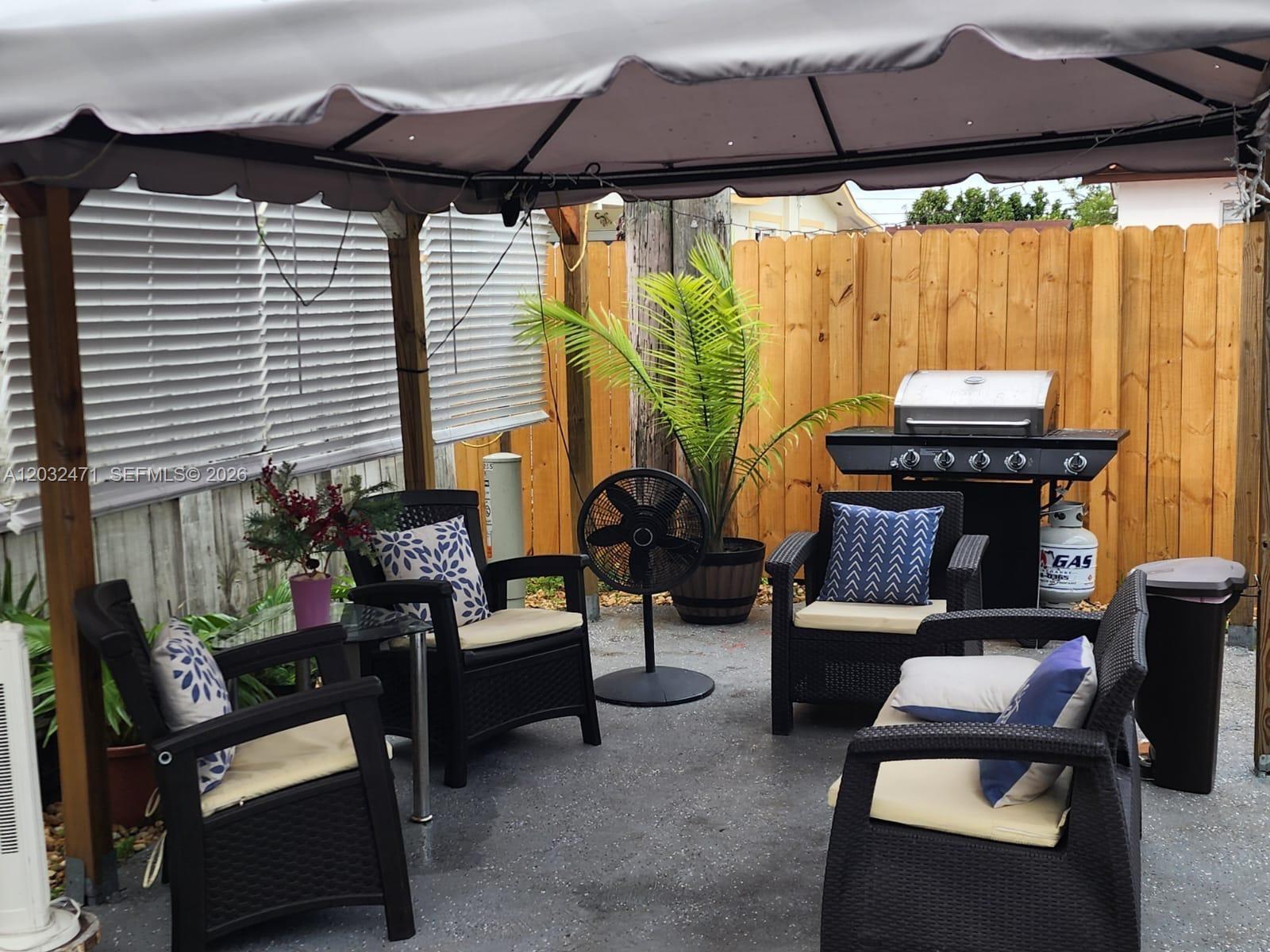 A covered outdoor patio features wicker furniture, a grill, and a potted palm tree — 11267 SW 7th St, Sweetwater FL 33174, SWEETWATER, FL