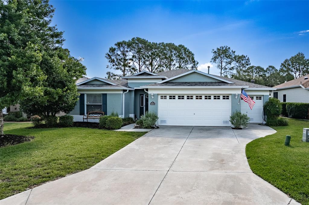 A single-story house with a white three-car garage, light blue siding, and a concrete driveway — 16023 SW 14TH AVENUE ROAD, OCALA, FL
