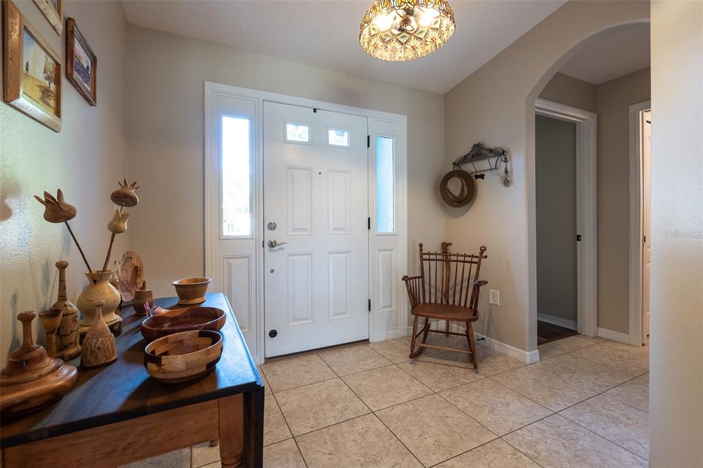 A foyer features tile flooring, a wooden rocking chair, and a console table with bowls — 16023 SW 14TH AVENUE ROAD, OCALA, FL