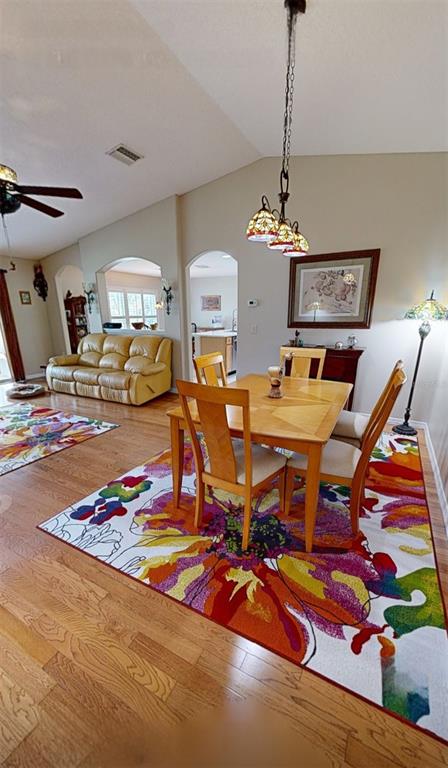 A dining area with a wooden table and chairs sits on a vibrant floral rug — 16023 SW 14TH AVENUE ROAD, OCALA, FL