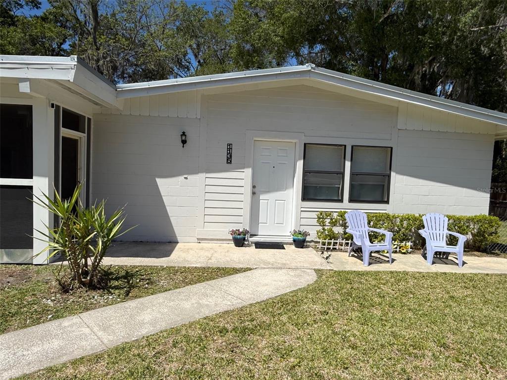 The exterior of a white, single-story house features a front door, two chairs, and landscaping — 1135 NEIL COURT, STARKE, FL