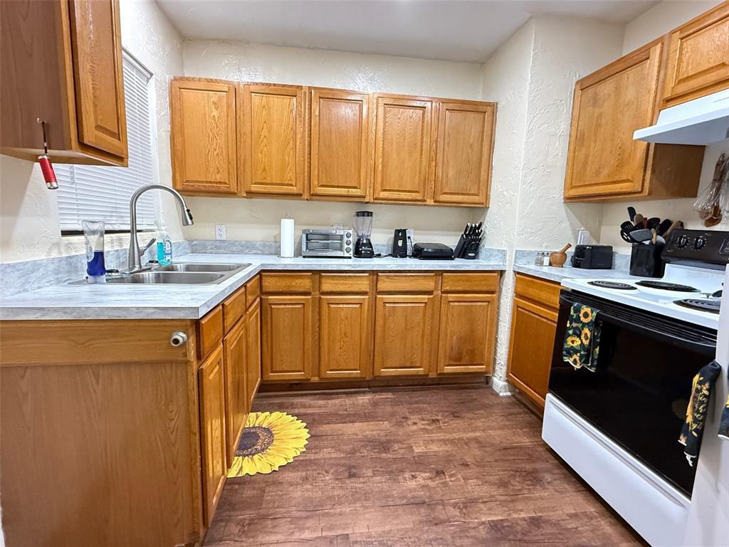 A kitchen features oak cabinets, light countertops, a double sink, and dark wood-look flooring — 1135 NEIL COURT, STARKE, FL