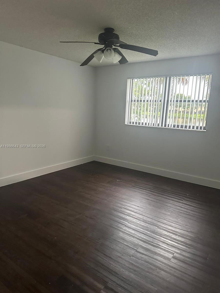 This empty bedroom features dark wood-look flooring, white walls, and a ceiling fan — 9777 Nob Hill Ct # 9777, Sunrise FL 33351, SUNRISE, FL