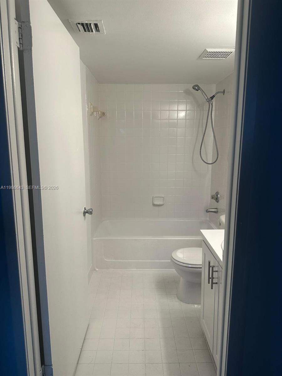 A small bathroom features a white tiled bathtub, a toilet, and a white vanity — 9777 Nob Hill Ct # 9777, Sunrise FL 33351, SUNRISE, FL