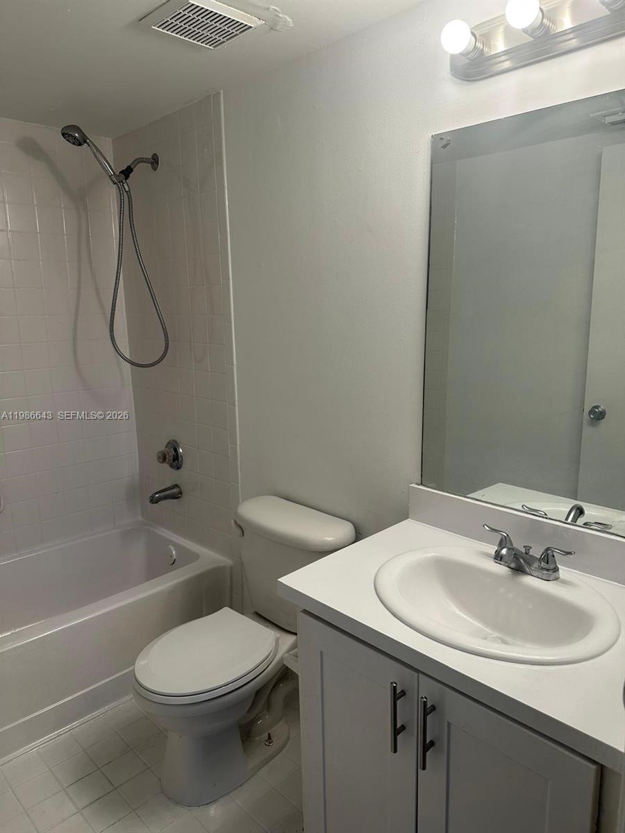 A bathroom features a white vanity, a toilet, and a shower-tub combination with white tiles — 9777 Nob Hill Ct # 9777, Sunrise FL 33351, SUNRISE, FL