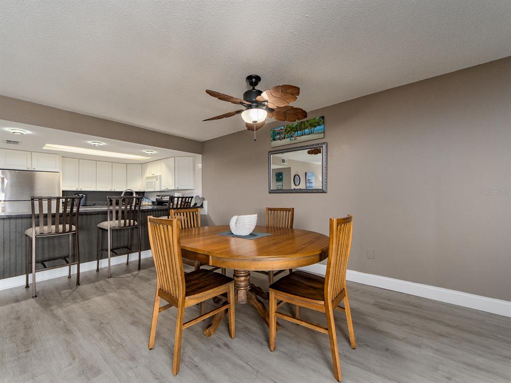 A dining area with a round wooden table, four chairs, and a ceiling fan — 19610 GULF BOULEVARD UNIT 303, INDIAN SHORES, FL